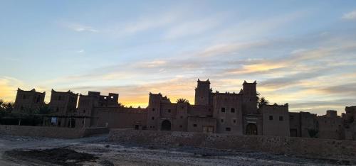 un grand château avec un coucher de soleil en arrière-plan dans l'établissement Kasbah Ait ben Damiette, à Skoura