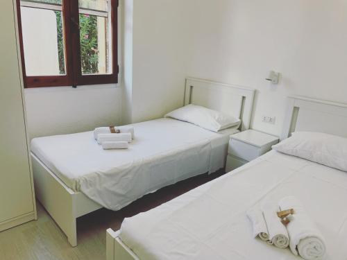 Dos camas en una habitación con paredes y ventanas blancas. en Villino Oleandro a pochi passi dalla spiaggia di Simius, en Simius