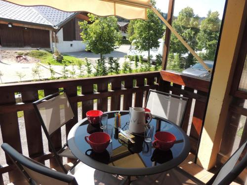 - une table sur un balcon avec des tasses rouges dans l'établissement Bel appartement 3 pièces aux Gets, proche pistes et centre, équipé tout confort, capacité 4 pers. - FR-1-598-17, aux Gets