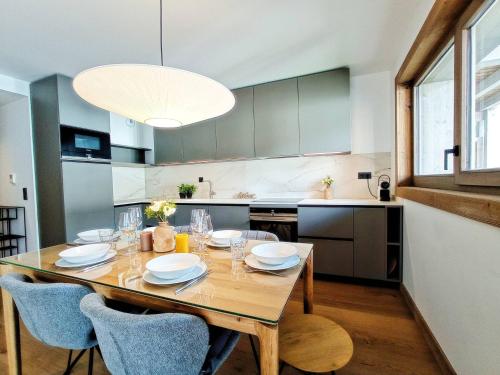 une cuisine avec une table en bois, des chaises et un grand éclairage dans l'établissement Appartement chaleureux 3 chambres au coeur des Gets avec Wifi, proche pistes - FR-1-598-78, aux Gets
