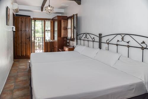 una camera da letto con un grande letto con lenzuola bianche di Hotel Rural Xerete a Navaconcejo