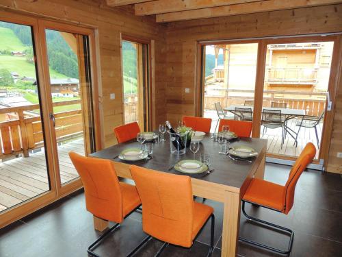 - une salle à manger avec une table et des chaises orange dans l'établissement Chalet chaleureux 4* aux Gets, 3 niveaux, 6 pers., terrasse, poêle à bois, wifi - FR-1-598-10, aux Gets