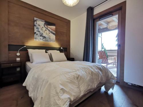 une chambre avec un grand lit et une grande fenêtre dans l'établissement Appartement neuf 54m² Les Gets, centre, balcon sud-ouest, Wifi, parking - FR-1-598-70, aux Gets