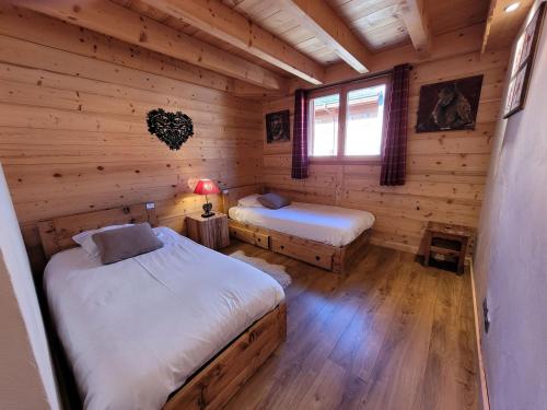 a bedroom with two beds in a log cabin at Appartement spacieux, 3 pièces + mezzanine, parking, Wifi - FR-1-598-79 in Les Gets
