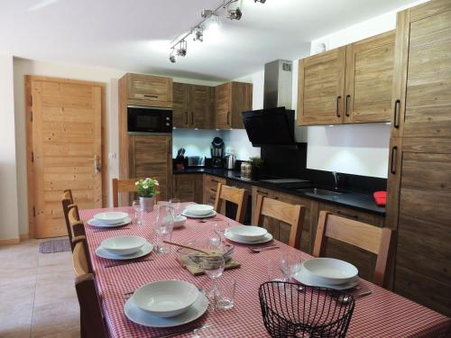 une cuisine avec une table avec des assiettes et des verres dessus dans l'établissement Grand appartement familial avec garage et WiFi, 3 chambres pour 8 personnes - FR-1-598-55, aux Gets