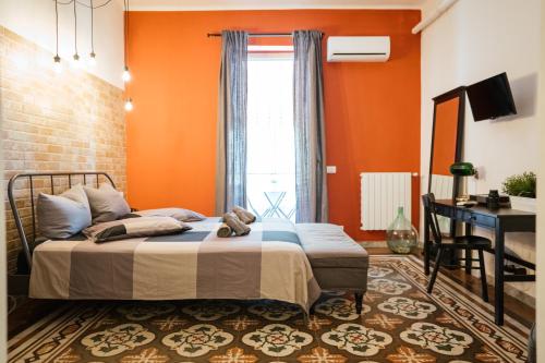 バーリにあるArt Nouveau apartmentのオレンジ色の壁のベッドルーム1室、ベッド1台、デスクが備わります。