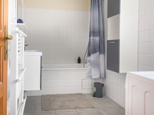 a white bathroom with a tub and a shower at Fééria - Appartement au calme proche de Disneyland Paris in Chessy