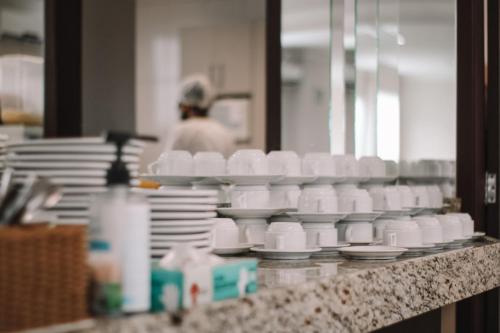 a counter with white cups and plates on it at Avenida Palace Hotel in Joinville