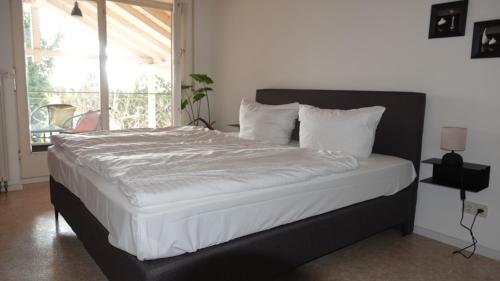 Una cama con sábanas blancas y almohadas en un dormitorio en Casa Luna, en Ballrechten