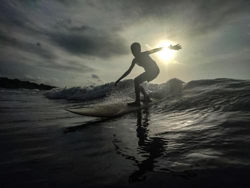 una persona montando una ola en una tabla de surf en el océano en Chowa lodge en Nuquí