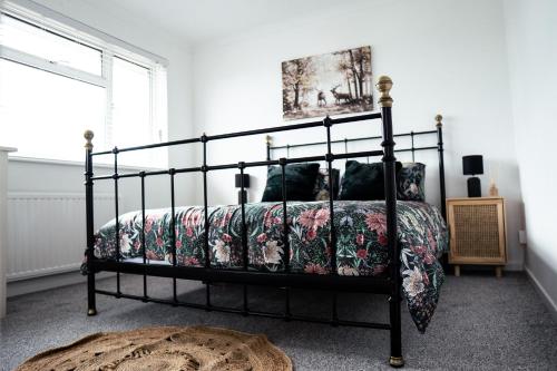 a bedroom with a black bed with a floral bedspread at Large 4 BedroomProperty driveway and 3 bathrooms in Burton Latimer