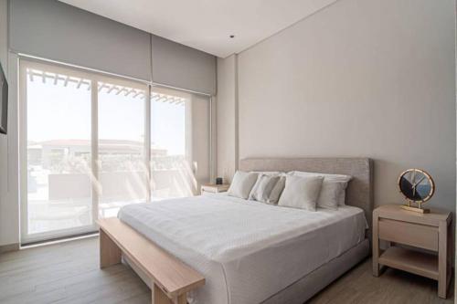 a white bedroom with a large bed and a window at Amazing Cabo Marina condo with private jacuzzi in Cabo San Lucas