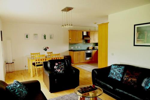 a living room with two black couches and a kitchen at Donard Holidays in Newcastle