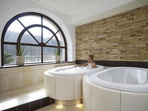 a child sitting in a bath tub in a bathroom at Naturhotel Rügers Forstgut in Mespelbrunn