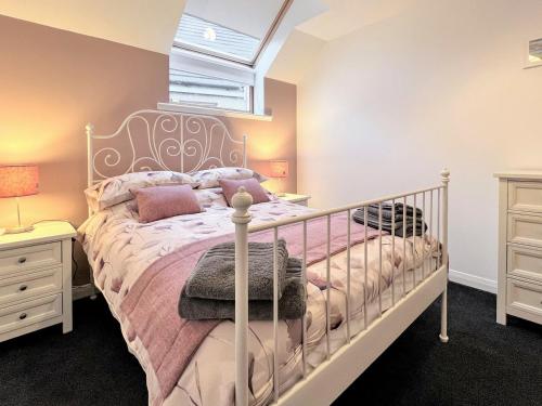 a bedroom with a white bed with pink pillows at Maries Hoose in Stornoway