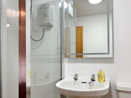 a white bathroom with a sink and a shower at Maries Hoose in Stornoway