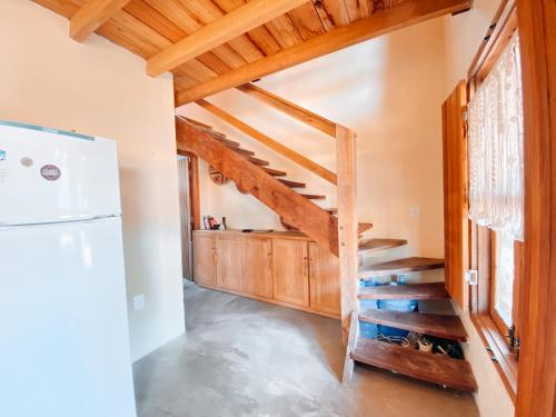 a staircase in a kitchen with wooden ceilings and a refrigerator at Caramuru Hostel Caraíva in Caraíva