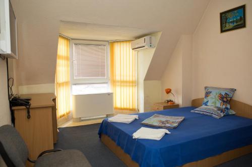 a bedroom with a blue bed and a window at Hotel Deva in Sandanski