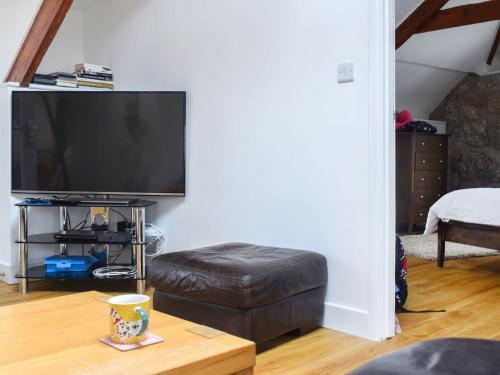 a living room with a flat screen tv and a stool at First Floor The Hayloft in Porthcurno