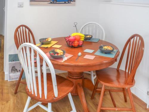 a wooden table with chairs and a bowl of fruit on it at First Floor The Hayloft in Porthcurno
