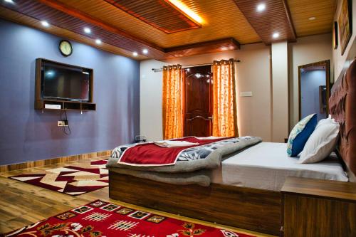 a bedroom with a bed and a flat screen tv at Traditional Hotel & Restaurant in Darjeeling