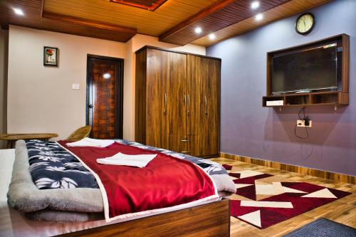a bedroom with a bed and a flat screen tv at Traditional Hotel & Restaurant !! Kurseong !! Best Hotel in Kurseong in Darjeeling