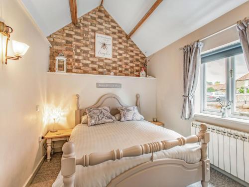 1 dormitorio con cama y pared de ladrillo en Barwick Lodge en Bawdeswell