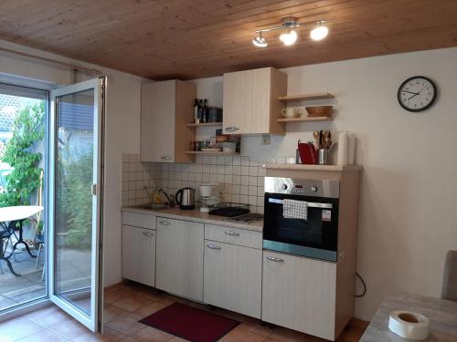 una cocina con armarios blancos y un reloj en la pared en Ferienwohnung Aichelberg, en Aichelberg