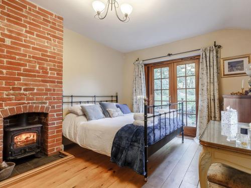 a bedroom with a bed and a brick fireplace at Manor Cottage Bungalow in Wetheringsett