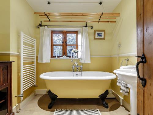 a claw foot tub in a bathroom with a sink at Manor Cottage Bungalow in Wetheringsett