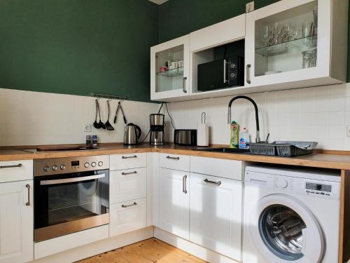 a kitchen with white cabinets and a washer and dryer at "HOGULU" Brandenburg, Hauptbahnhof, Küche in Brandenburg an der Havel