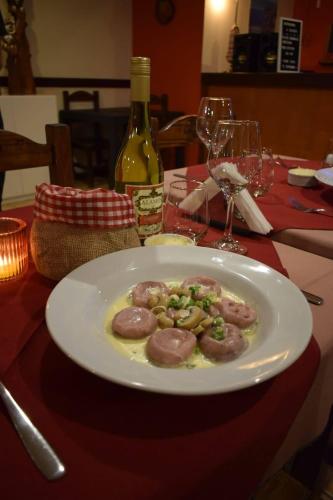 a plate of food on a table with a bottle of wine at Hotel Mora in Los Antiguos