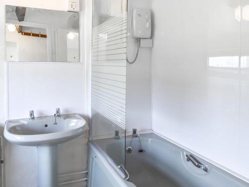 a white bathroom with a sink and a bath tub at Tyn Y Maen in Llanddeiniolen