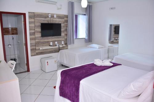 a hotel room with two beds and a tv at Hotel Açay in Santarém