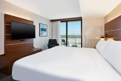 a hotel room with a large bed and a flat screen tv at Holiday Inn Express & Suites VA Beach Oceanfront by IHG in Virginia Beach