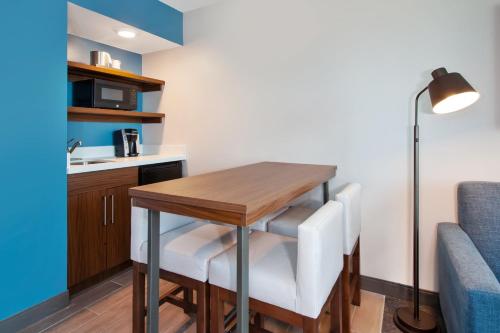 a small kitchen with a wooden table and white chairs at Holiday Inn Express & Suites VA Beach Oceanfront by IHG in Virginia Beach