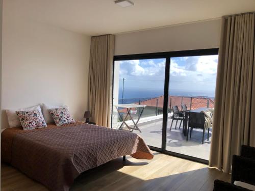 ein Schlafzimmer mit Bett und Balkon mit Aussicht in der Unterkunft Calheta Ocean View Family Apartment - Air Condition in Estreito da Calheta