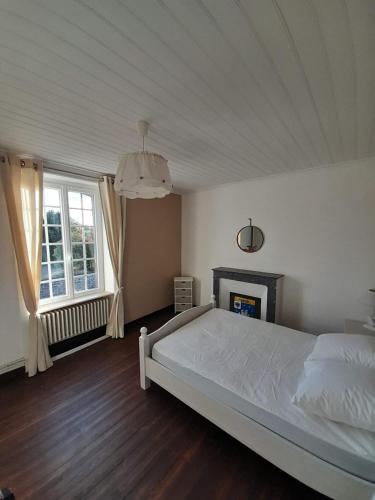 1 dormitorio con cama blanca y chimenea en Rozéliande, en Roz-sur-Couesnon