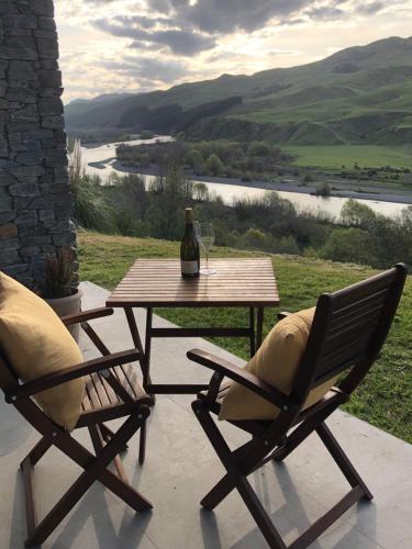 two chairs and a table with a bottle of wine at River View Cottage in Kahuranaki
