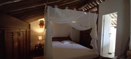 a bedroom with a canopy bed with white drapes at Casa Vila Do Outeiro in Praia do Espelho