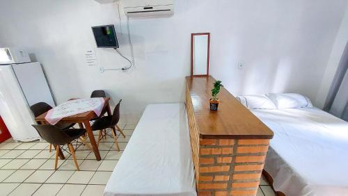 Habitación pequeña con cama, escritorio y mesa. en Residencial Bem Estar, en Bombinhas