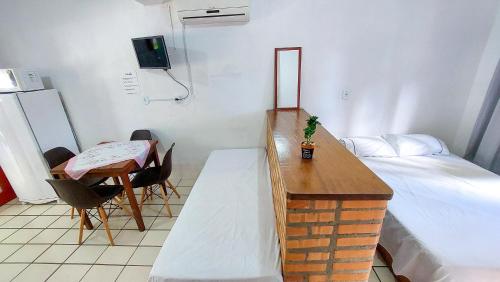 a small room with a bed and a desk and a table at Residencial Bem Estar in Bombinhas