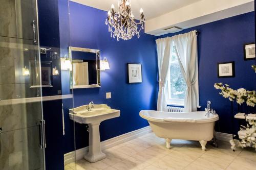 ein blaues Badezimmer mit einer Badewanne und einem Waschbecken in der Unterkunft Manoir Becancourt Hotel in Bécancour
