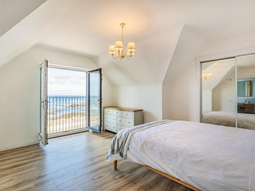 a white bedroom with a bed and a large window at Headland View in Banff