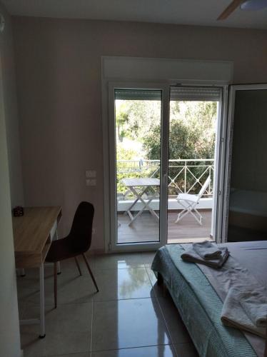 a bedroom with a bed and a desk and a balcony at Cozy villa Vita Lagonisi in Kalívia Thorikoú