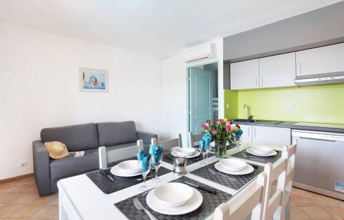 uma cozinha e sala de estar com mesa e cadeiras em Appartement La Palmeraie Odalys Prestige Grimaud em Grimaud