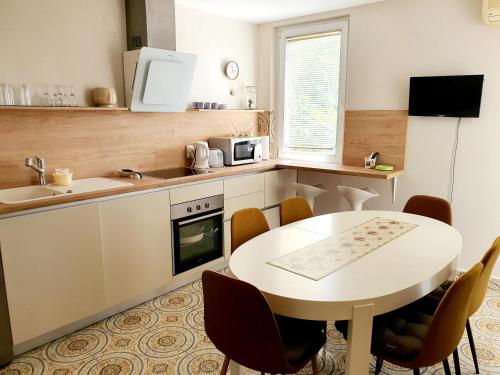 uma cozinha com uma mesa branca, uma mesa e cadeiras em Batala1-City marina apartment with secured private parking em Dubrovnik