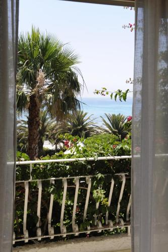 a window with a view of the ocean and palm trees at Hotel Simius Playa in Villasimius