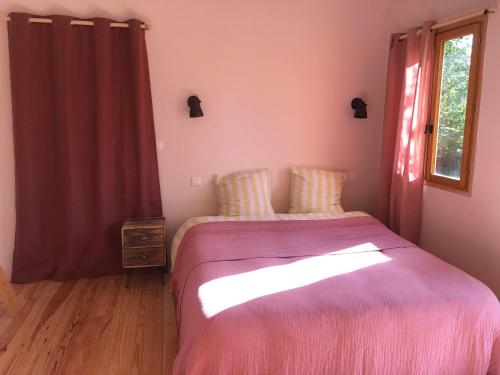 a bedroom with a bed with a pink blanket and a window at Tiny-House sous les arbres et les oiseaux 