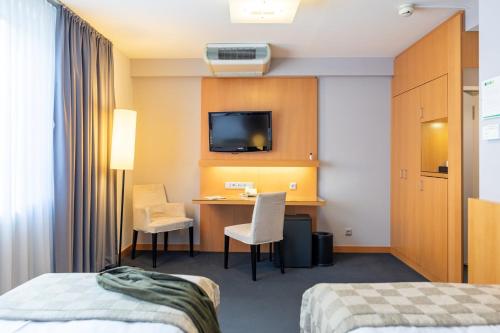 a hotel room with a desk and a tv at Holiday Inn Vienna City by IHG in Vienna